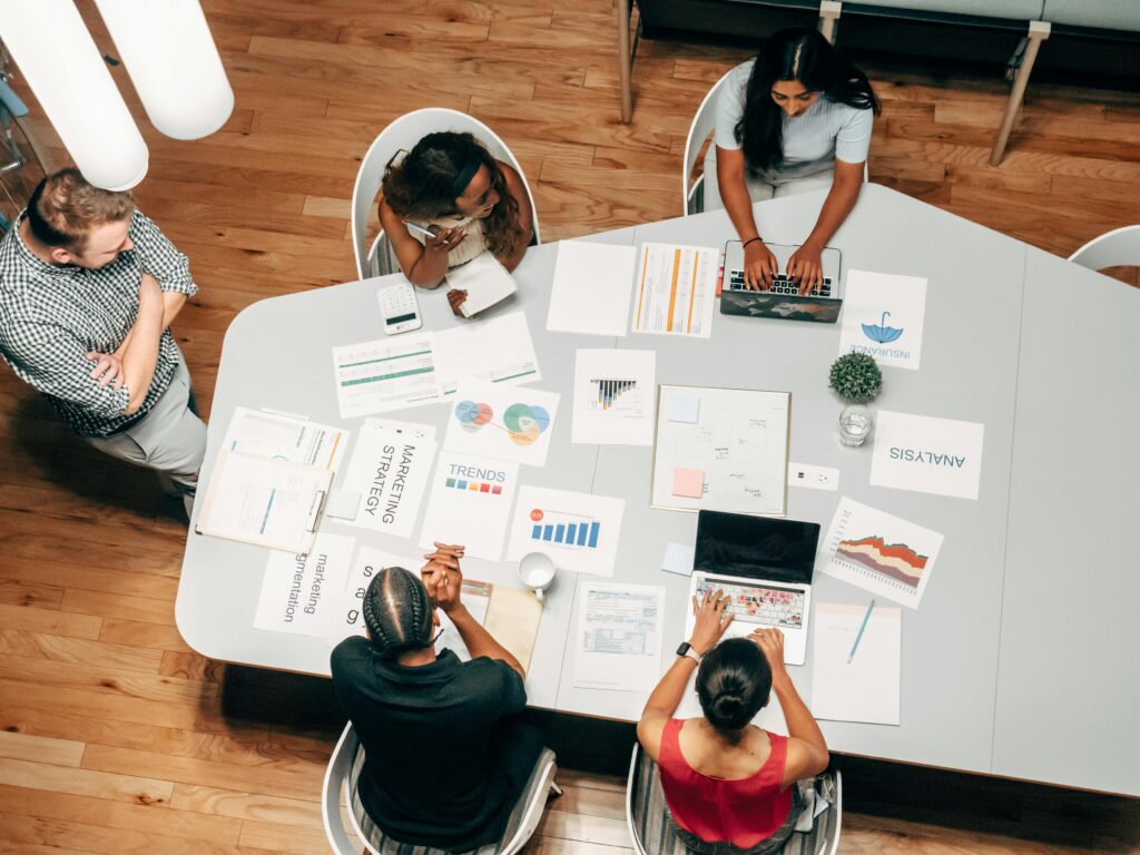 Grupo a trabalhar numa boa campanha de marketing digital com gráficos e computadores numa mesa de escritório.