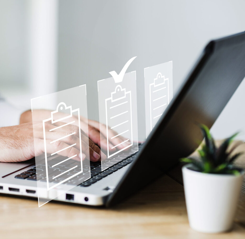 Computador-com-checks-simbolizando-formações-e-certificações Mãos ao computador com Tarefas concluídas, simbolizando a conclusão de Formações e Certificações