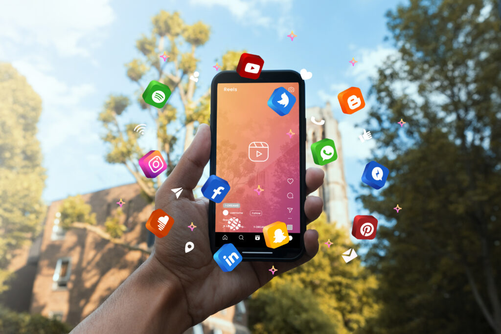 Mão de um Freelancer em Marketing Digital a segurar um telemóvel com vários ícones de redes sociais.