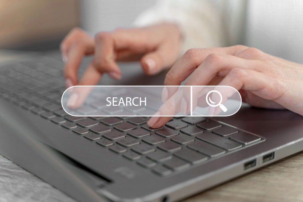 mãos-no-teclado-computador-com-search-consultora-SEO Consultora SEO - Mãos femininas num teclado de computador portátil com uma barra de search